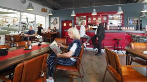 Een restaurant met lederen stoelen, een bar en uitzicht op oude vliegtuigen door grote ramen.