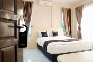 A hotel room with a bed, curtains, a door with a sign, and an air conditioning unit.