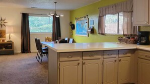 A kitchen with a central island, cabinets, a dining area with chairs, a coffee maker, and a map on the wall. - Quaint & Cozy Cottage: 3 Mi to Palisade Wineries! (Grand Junction)