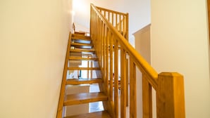 A wooden staircase with a handrail, leading to an upper floor.