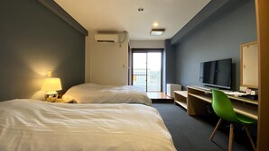 Habitación de hotel con dos camas, un escritorio con televisor y una silla verde.