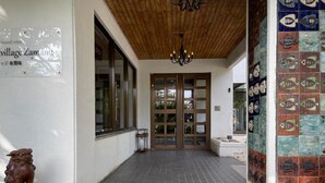 Entrada de un edificio con suelo de baldosas, techo de madera y un cartel.