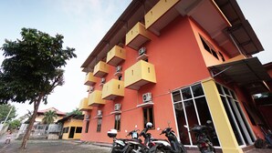 A multi-story building with balconies and air conditioning units. - OYO 2486 Bahana Guest House (Manado)