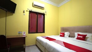 A hotel room with a bed, a desk, and a TV. - OYO 2486 Bahana Guest House (Manado)