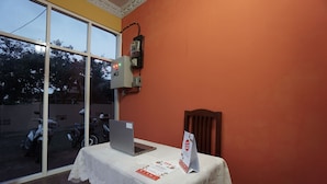A room with a table covered by a white lace tablecloth, a laptop, and a sign on the table. - OYO 2486 Bahana Guest House (Manado)