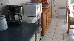 A kitchen with a coffee maker, a microwave, and a cabinet. - 50m from the sea Holiday house for 2 people in Dossen (Santec)