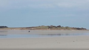A beach with a distant view of a hill with a building. - 50m from the sea Holiday house for 2 people in Dossen (Santec)