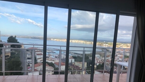 Een balkon met uitzicht op een kustplaats, inclusief een waterpartij en gebouwen.