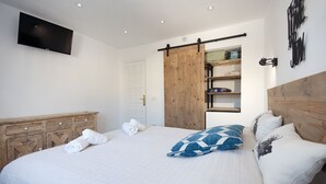 A bedroom with a bed, a TV mounted on the wall, a wooden wardrobe, and a sliding door closet. - Sara 6 P.- modern, family friendly, with private pool and private tennis court! (Benissa)