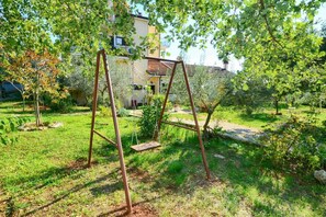 A swing set in a garden with a house in the background.