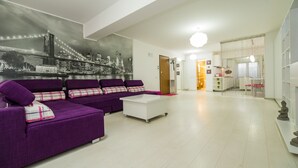 Una sala de estar moderna con un sofá modular, una mesita de centro y un mural con un paisaje urbano en la pared.