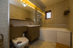 Een moderne badkamer met een glazen douchecabine, een wastafel met spiegel en een toilet met decoratieve klep.