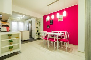 Una cocina moderna con armarios blancos y una pared de acento rosa.