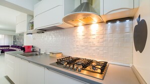 Una cocina moderna con estufa a gas, armarios blancos y salpicadero de azulejos.