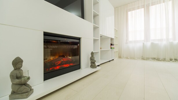 Una sala de estar moderna con chimenea, estanterías blancas y una estatua de Buda.