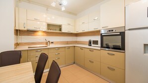 A modern kitchen with beige cabinets, a stainless steel oven, and a microwave. - Relax Apartment Coresi Mall (Brasov)