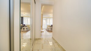 A hallway with a marble floor leading to a living area with a sofa and a coffee table. - Relax Apartment Coresi Mall (Brasov)