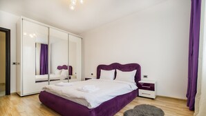 A bedroom with a large bed, a wardrobe, a nightstand, and a fluffy rug. - Relax Apartment Coresi Mall (Brasov)