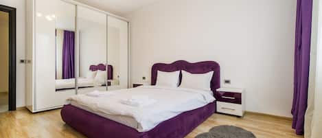 A bedroom with a large bed, a wardrobe, a nightstand, and a fluffy rug.