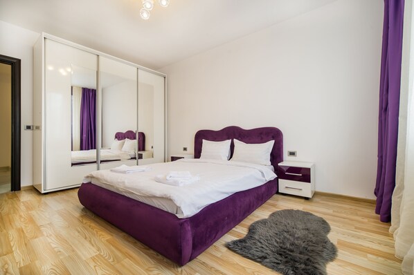 Une chambre avec un grand lit, une armoire, une table de chevet et un tapis moelleux.
