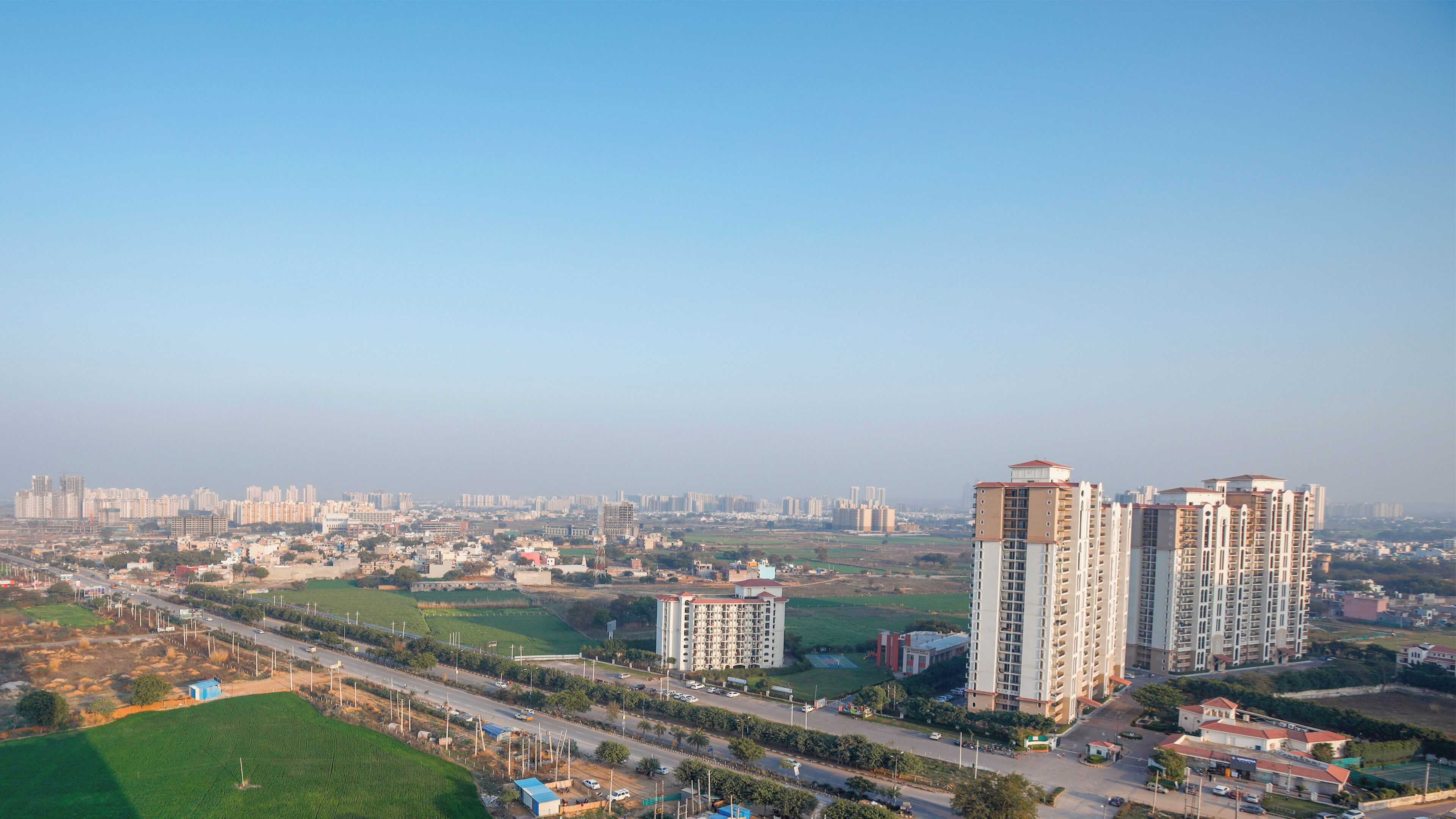A high-rise residential building with multiple floors, surrounded by a mix of low-rise buildings and open green spaces.