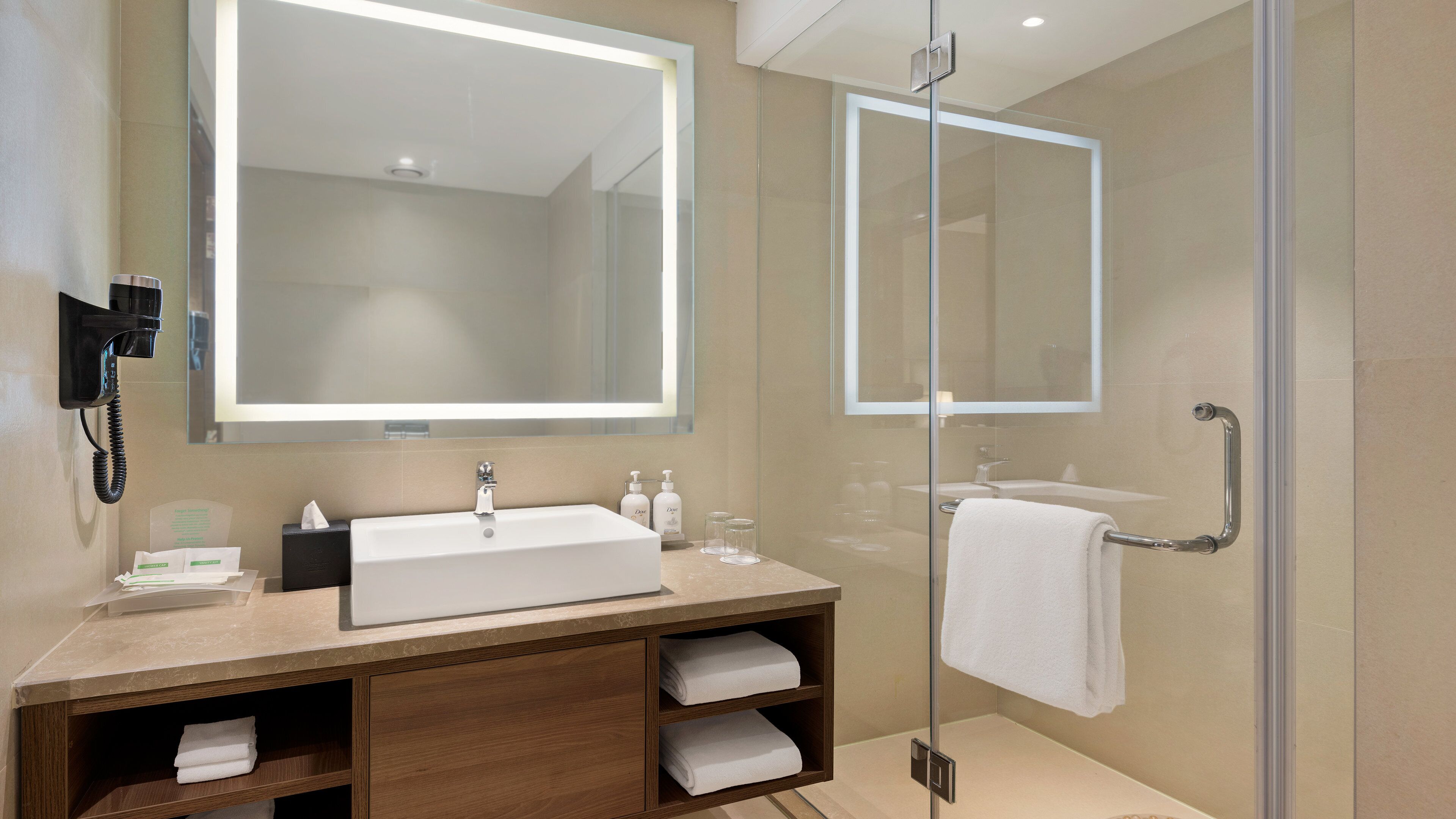 A modern bathroom with a large mirror, a sink, and a glass shower enclosure.