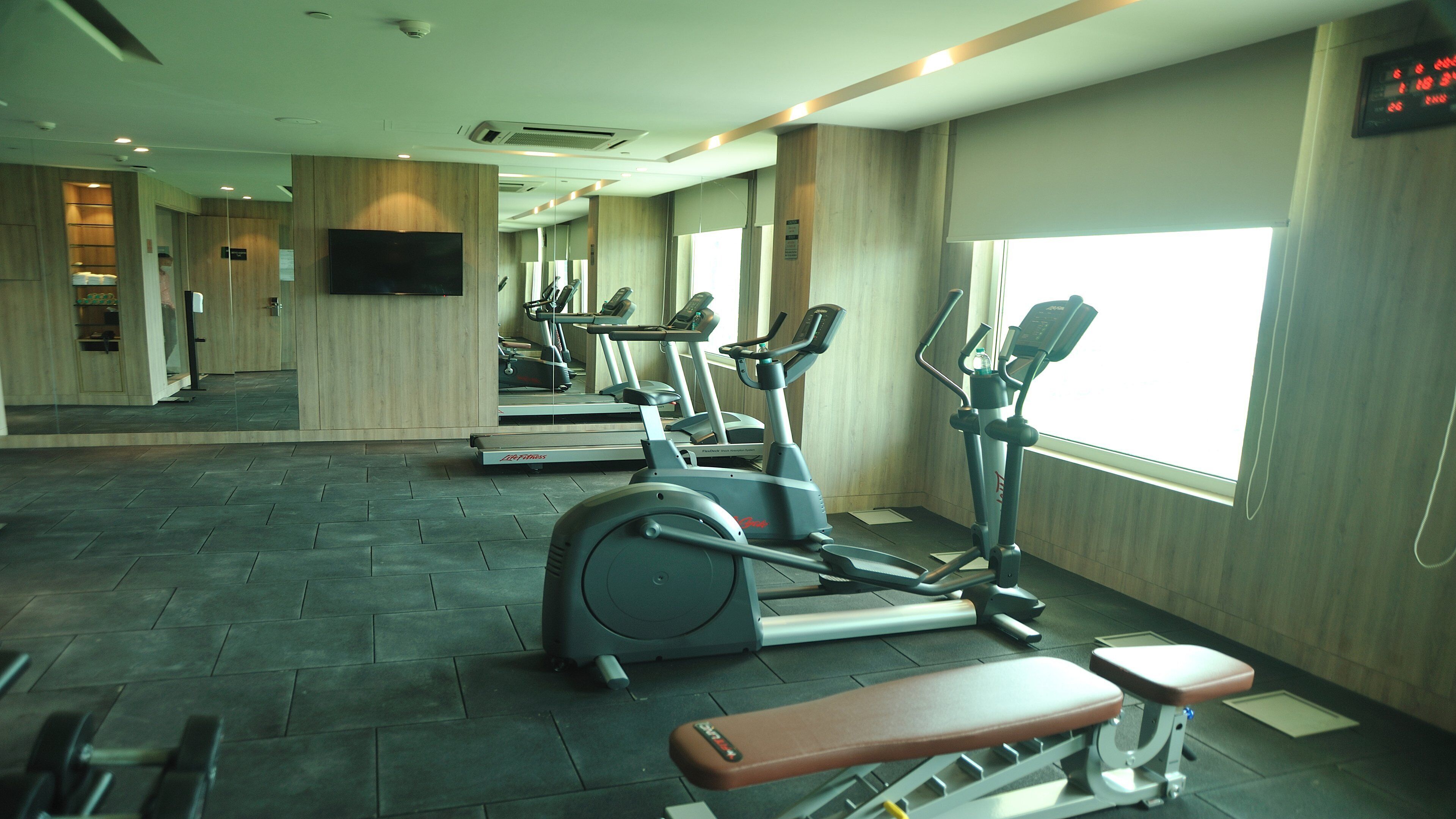 Un gimnasio con cintas de correr, elípticas y una banca.