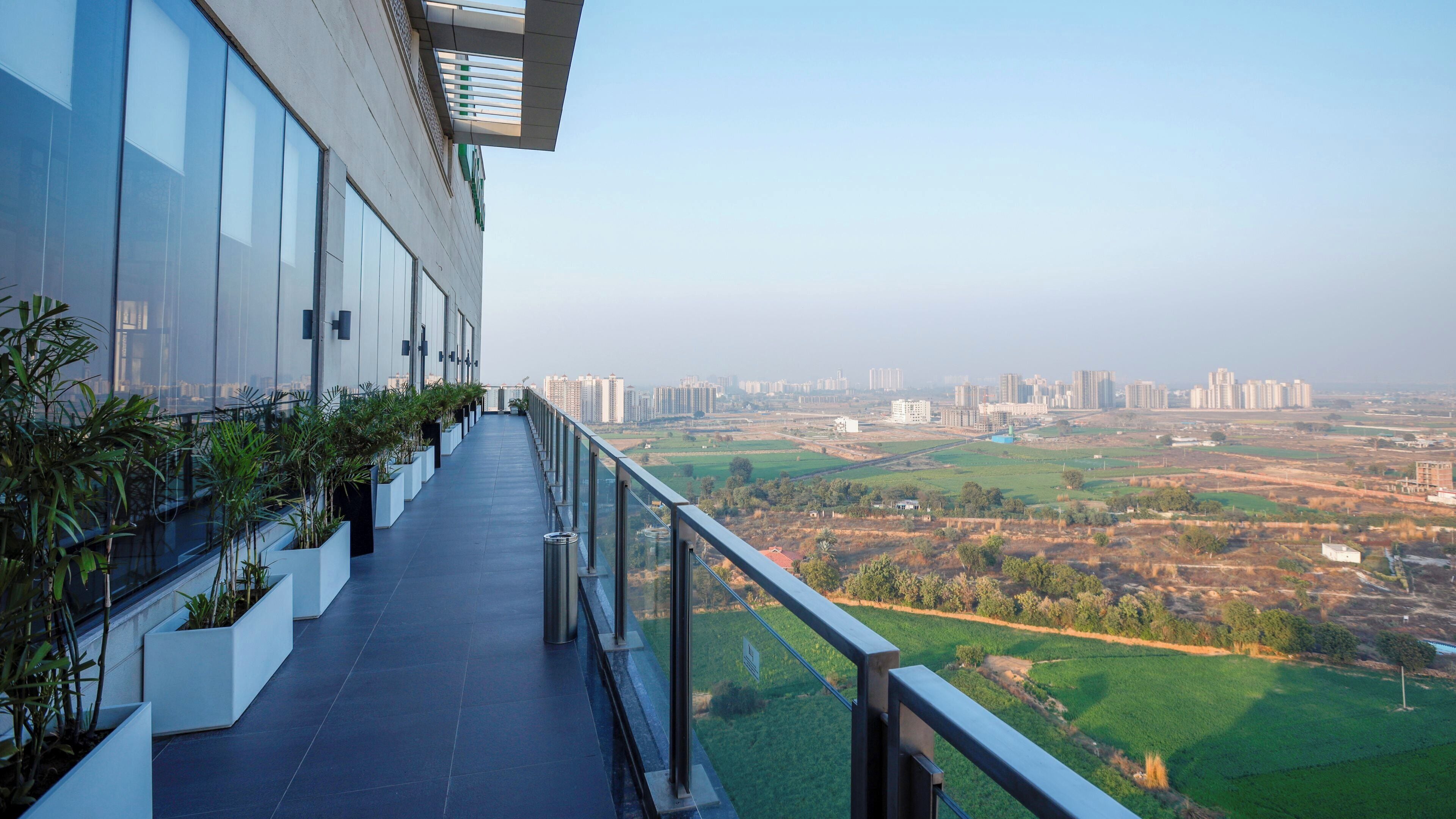 Un balcón con vista a un paisaje urbano y campos verdes.