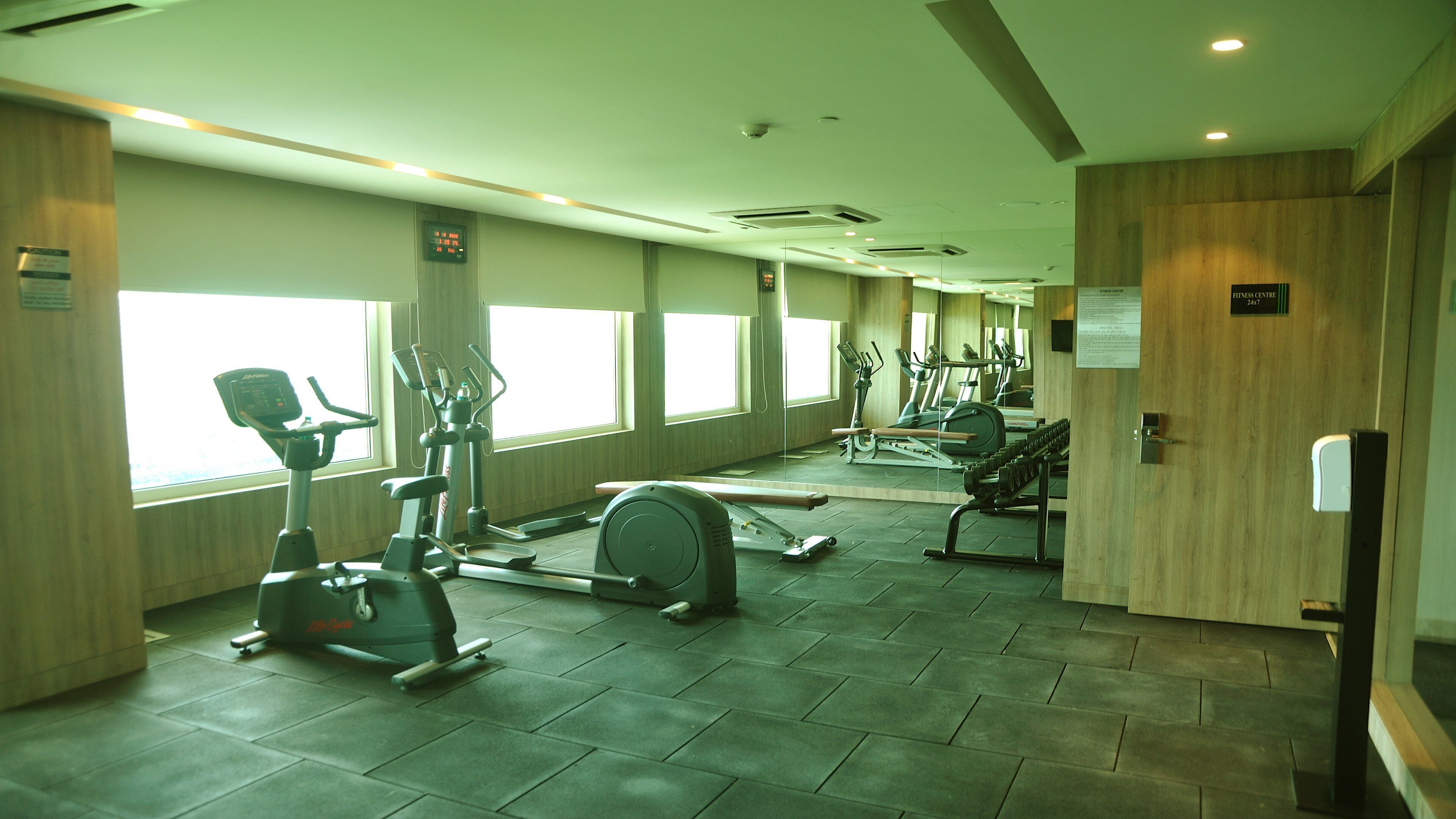 A gym with cardio machines, weight stations, and a mirror wall.