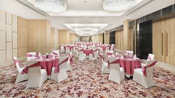 A banquet hall with round tables, white chairs, and pink tablecloths.