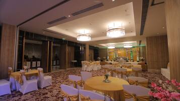 A banquet hall with round tables and white chairs, adorned with gold sashes.