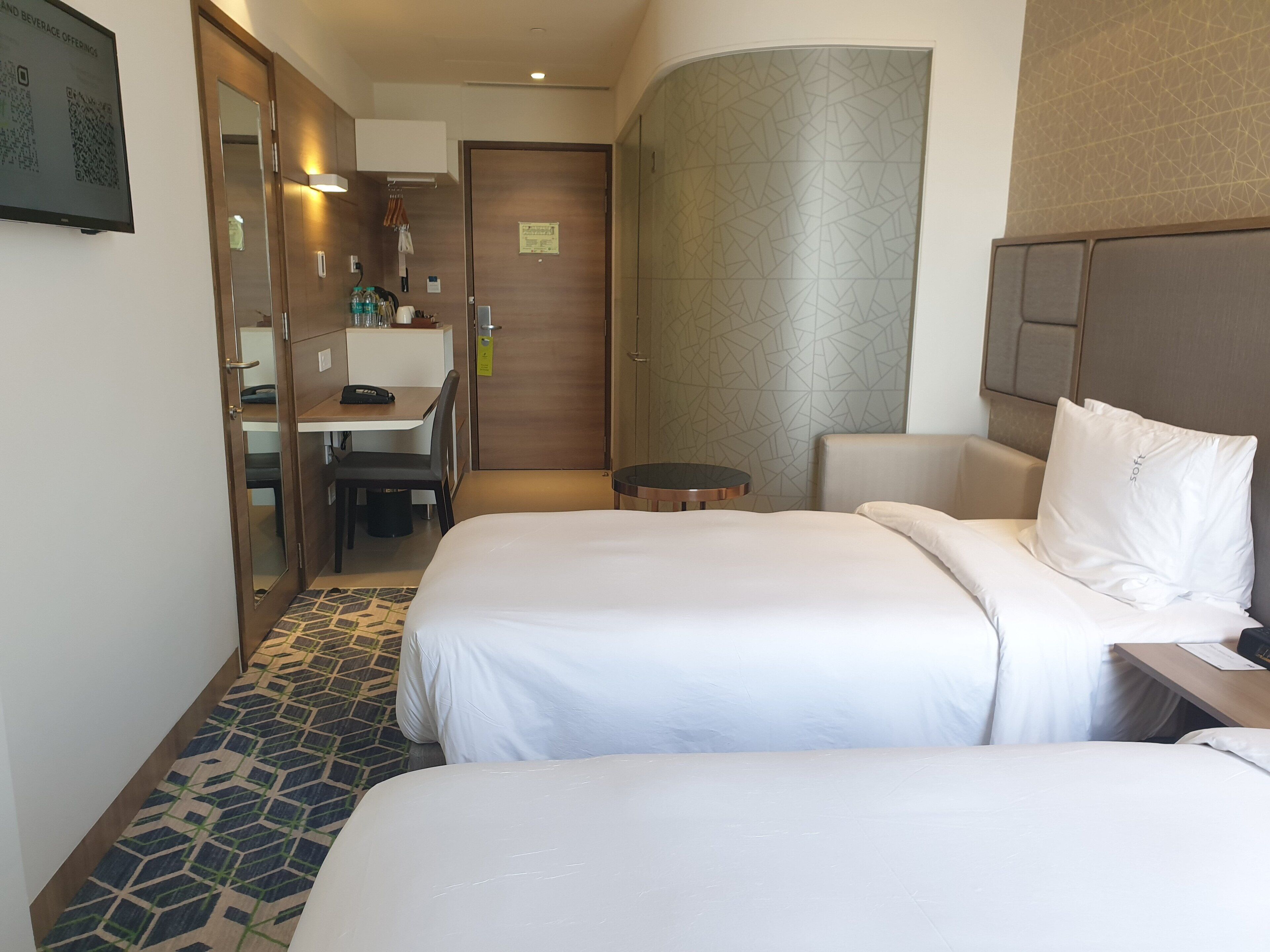 Een hotelkamer met twee bedden, een bureau en een stoel.