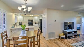 Une cuisine moderne avec des meubles blancs, un îlot central et un coin repas comprenant des chaises et une table en bois.