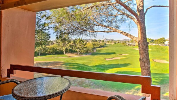 Un balcon donnant sur un terrain de golf, avec une table et une chaise.