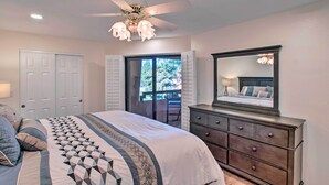 Une chambre à coucher comprenant un lit, une commode, un ventilateur de plafond et une vue sur l’extérieur.