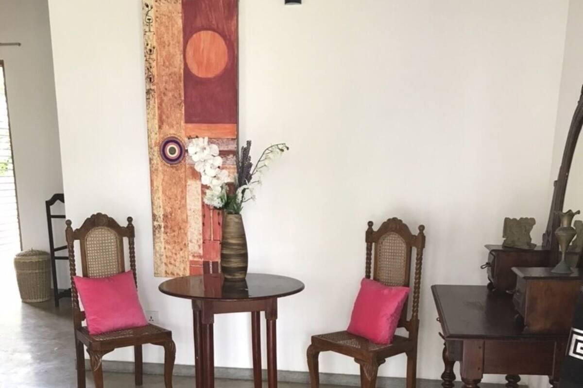 Un comedor con dos sillas de madera y una mesa, un adorno en la pared y suelo de hormigón.