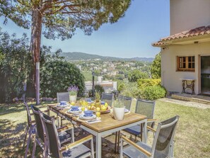 Mesa de comedor al aire libre con vista a un pueblo y colinas al fondo.