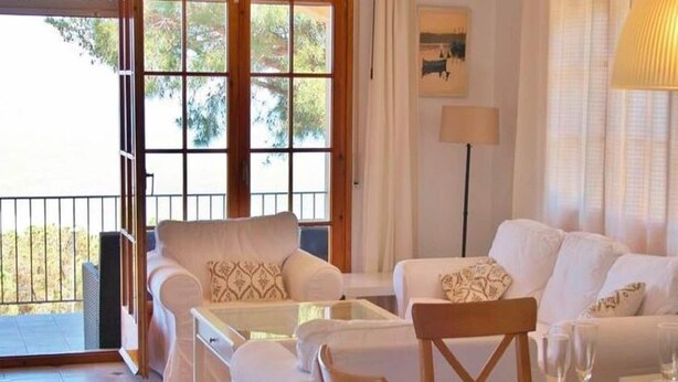 Un vaste espace de vie comprenant un canapé, des fauteuils et une table à manger dressée pour le repas.
