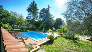 A swimming pool surrounded by greenery, with sun rays visible. - Umag-Valica, apartment for couples, near the beach, with a pool and barbecue (Umag)