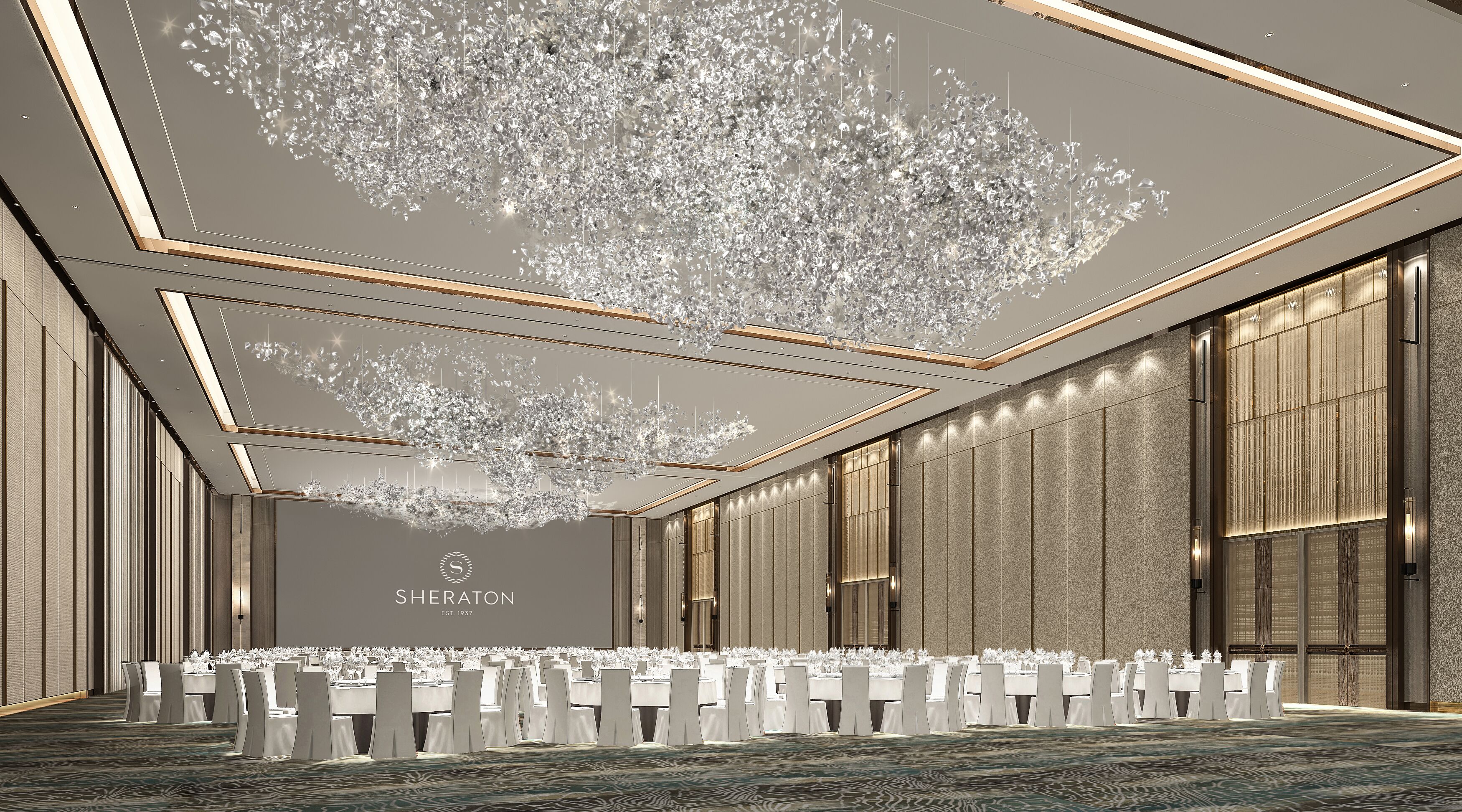 A spacious conference room with a high ceiling, large windows, and a modern chandelier. Tables are set for a formal event.