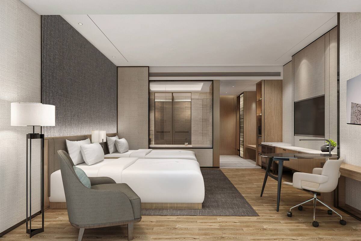 Ein modernes Hotelzimmer mit einem großen Bett, einem Schreibtisch, einem Sessel und einem Fernseher.