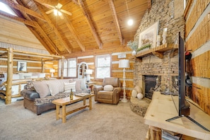 Ein gemütliches Blockhaus-Interieur mit Kamin aus Stein, Holzmöbeln und einem Fernseher.