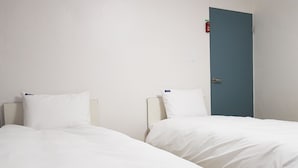 Two single beds with white bedding in a room with a blue door and a white wall. - Bluemoon Guest House - Hostel (Taebaek)