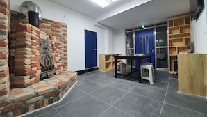 A room with a brick fireplace, a blue door, and a wooden desk with a computer. - Bluemoon Guest House - Hostel (Taebaek)