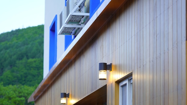 A wooden building with multiple balconies and windows, some with external lighting. - Bluemoon Guest House - Hostel (Taebaek)