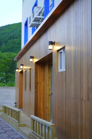 A wooden building with multiple balconies and windows, some with external lighting.