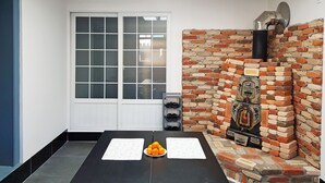 A room with a black table, a whiteboard, and a plate of oranges. There is a brick wall with a chimney and a window with frosted glass. - Bluemoon Guest House - Hostel (Taebaek)