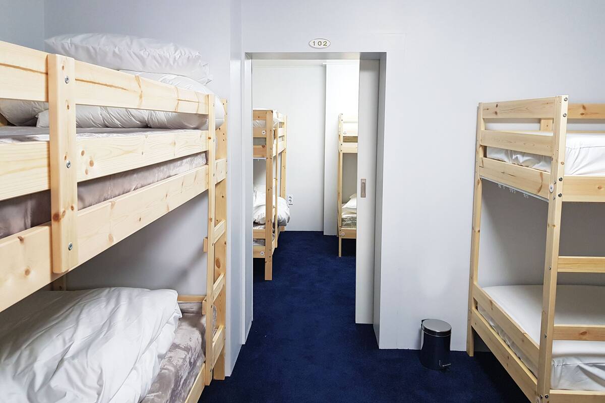 Habitación tipo dormitorio con literas, alfombra azul y una puerta con el número 102.