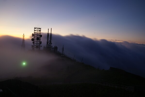 A telecommunications tower complex on a foggy mountain ridge.