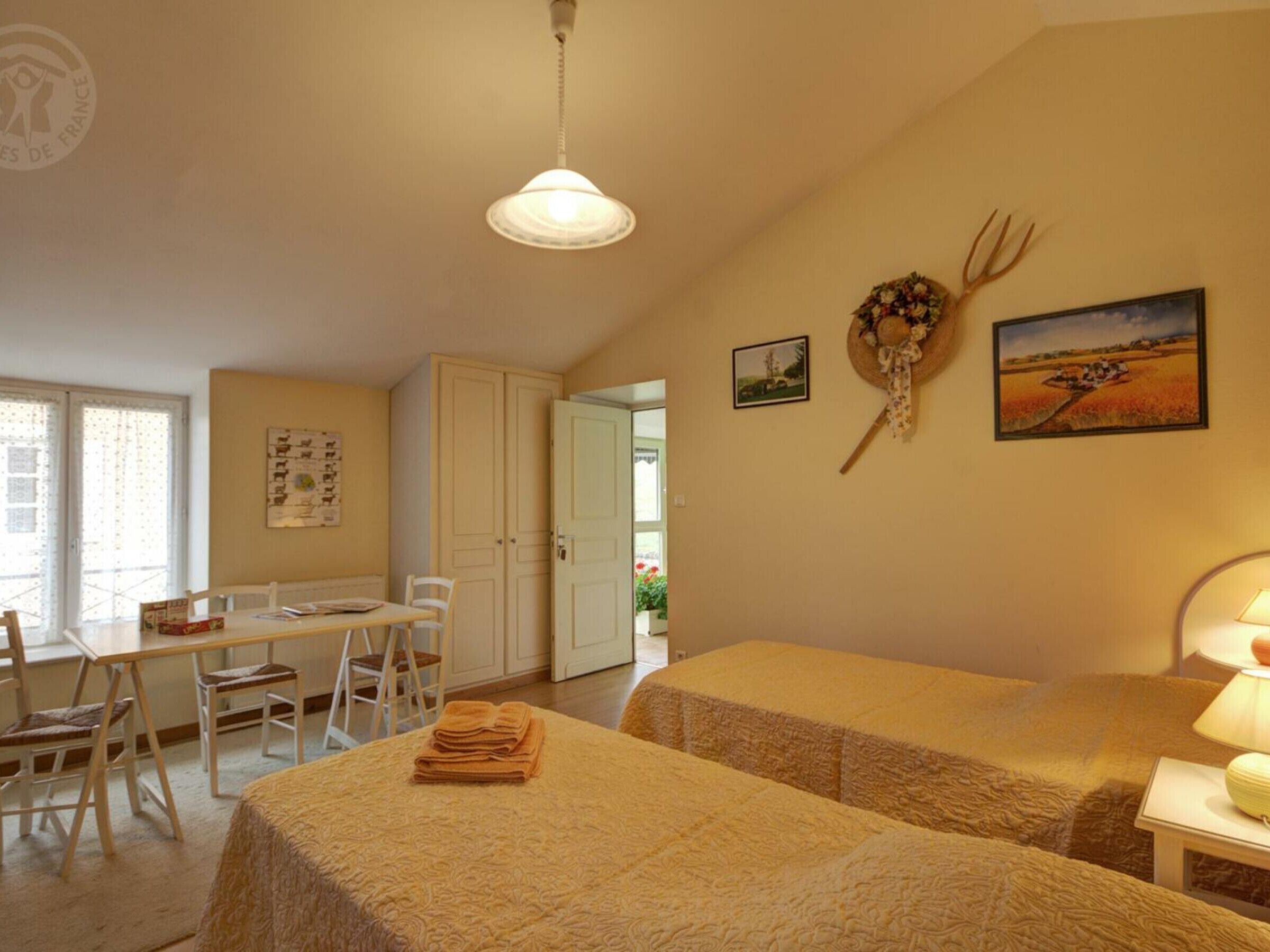 Una habitación con dos camas, una mesa de comedor con sillas, una zona de cocina y una puerta que da a otra habitación.
